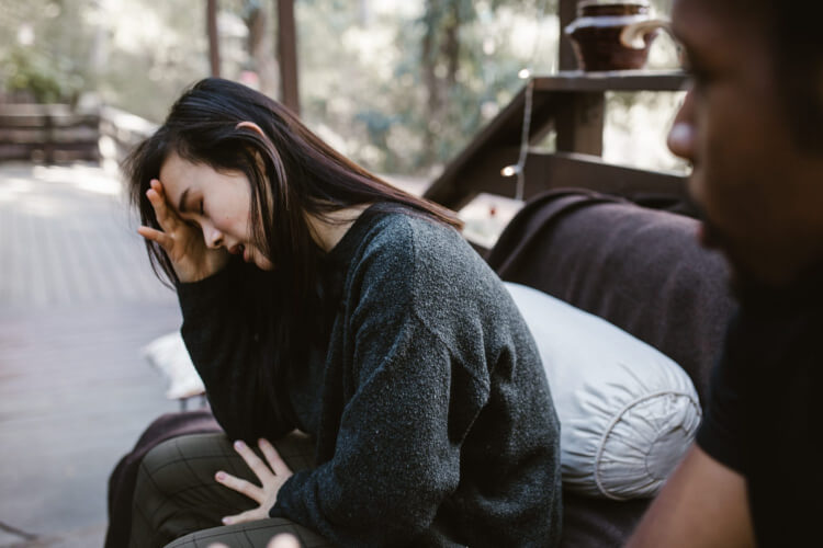 Woman sitting slouched with her hand on head