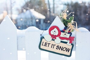 Let It Snow sign hanging on fence outside