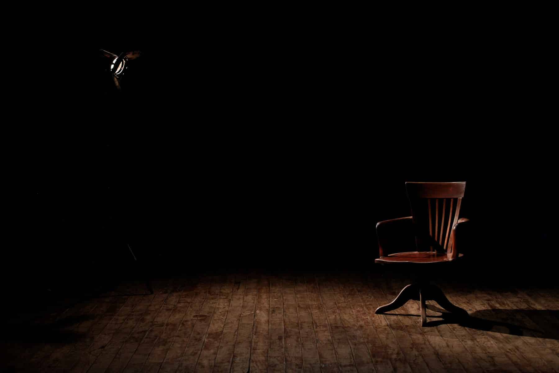 Dark room with one chair and a light shining on it