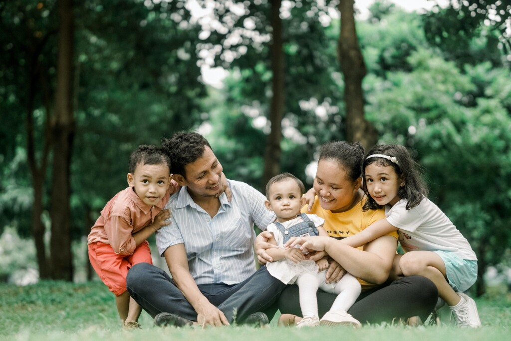 Family of 5 people sitting in the grass