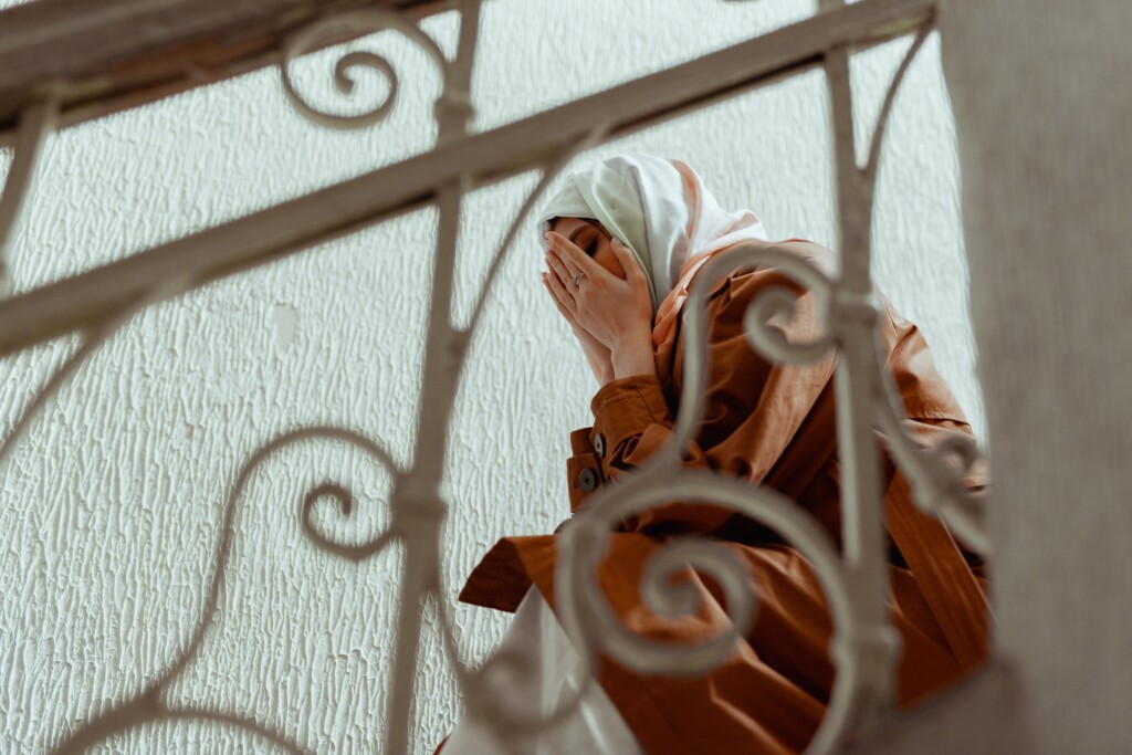 Woman with her face in her hands sitting on stairs